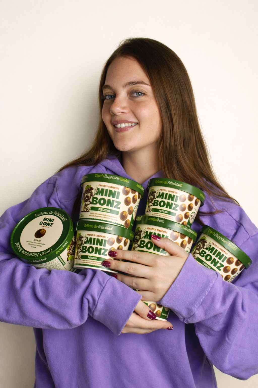 founder Kiana Mitre holding multiple containers of Mini Bonz pet food against a plain background